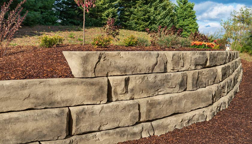 Large-format retaining wall with a snapped-stone face beside a planted bed